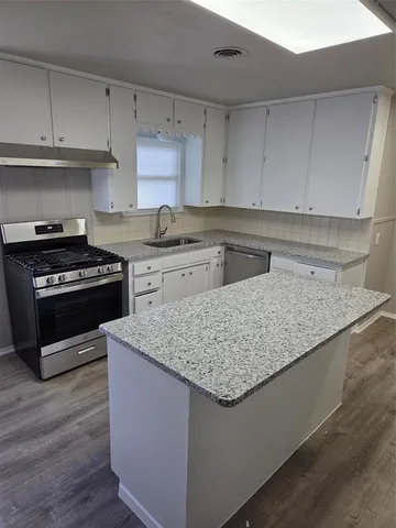 a kitchen with stainless steel appliances granite countertop a sink stove and cabinets