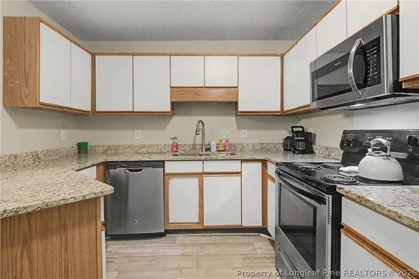 a kitchen with granite countertop wooden cabinets and a stove top oven