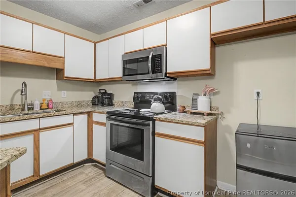 a kitchen with stainless steel appliances granite countertop a stove a sink and a microwave