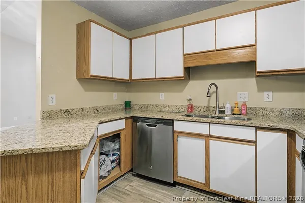 a kitchen with granite countertop a sink a stove and cabinets