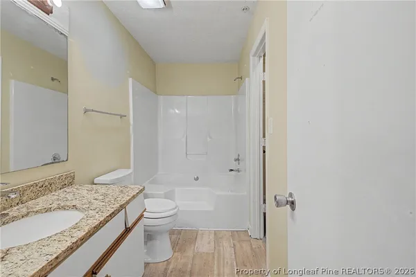 a bathroom with a granite countertop sink a toilet and shower