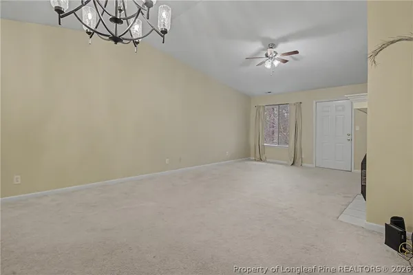 a view of an empty room with a chandelier fan