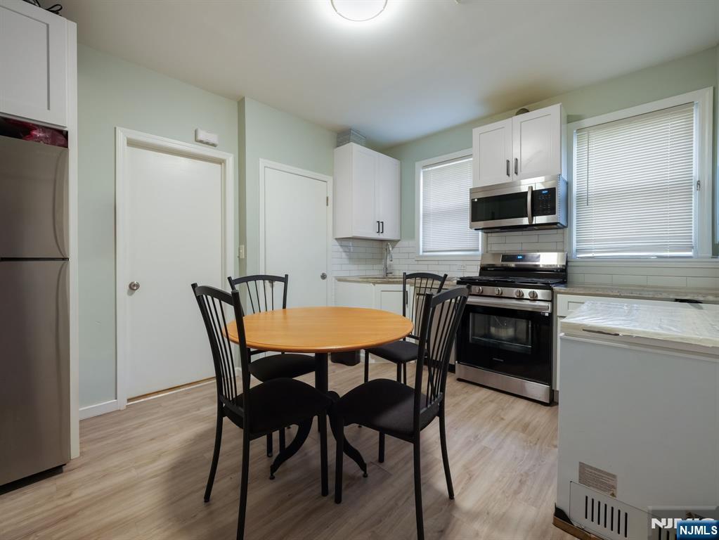 413 Lanza Avenue Garfield, NJ 07026 - Photo 18 of 37 a kitchen with stainless steel appliances a table chairs microwave and refrigerator