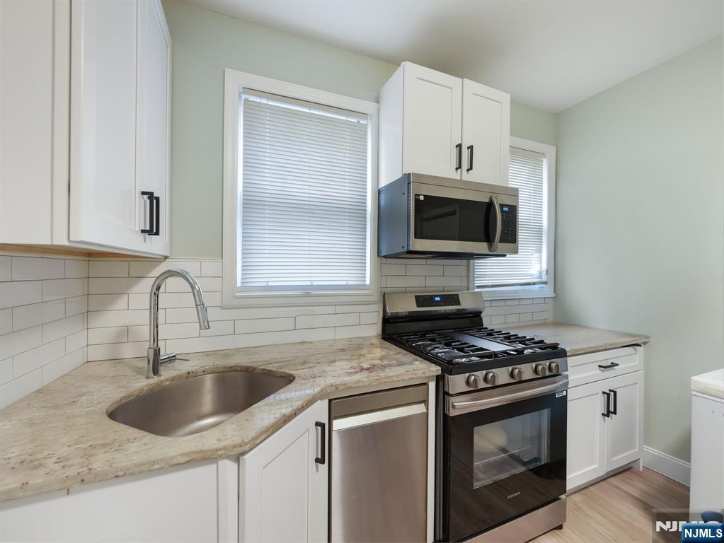 413 Lanza Avenue Garfield, NJ 07026 - Photo 20 of 37 a kitchen with granite countertop a sink stove and microwave