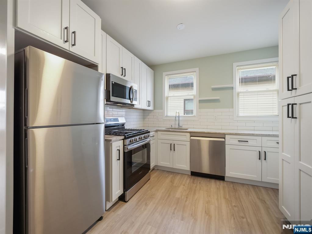 413 Lanza Avenue Garfield, NJ 07026 - Photo 2 of 37 a kitchen with stainless steel appliances granite countertop a refrigerator stove a sink and dishwasher with wooden floor