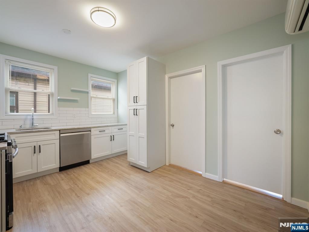 413 Lanza Avenue Garfield, NJ 07026 - Photo 8 of 37 a large white kitchen with a sink wooden floor and a large window