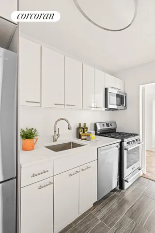 a kitchen with stainless steel appliances granite countertop a sink a stove a refrigerator with white cabinets and wooden floor