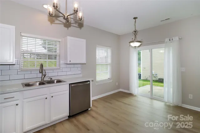 a kitchen with a sink chandelier and wooden floor
