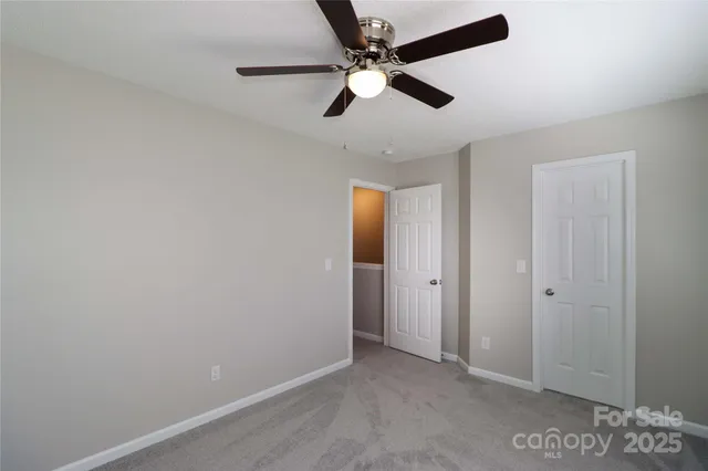 an empty room with a ceiling fan and carpet