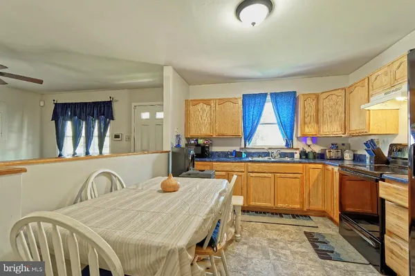 a kitchen with stainless steel appliances granite countertop a stove a sink dishwasher a dining table and chairs with wooden floor