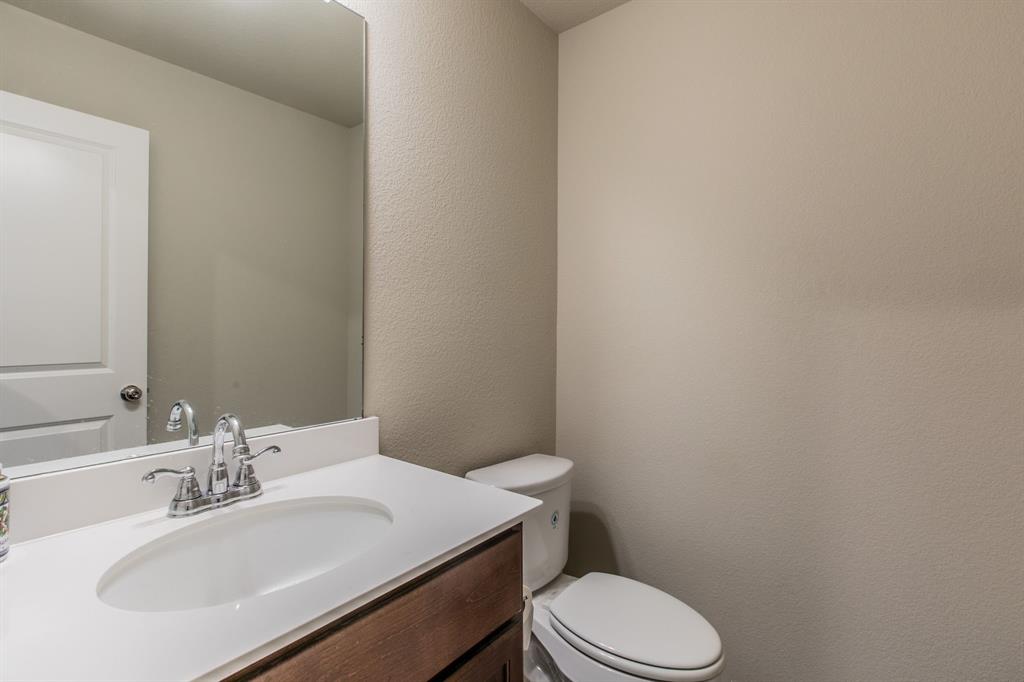2521 Maidenhair Road Frisco, TX 75033 - Photo 27 of 39 Bathroom featuring a white oval sink with chrome faucet, a white countertop, and wood-finish cabinetry