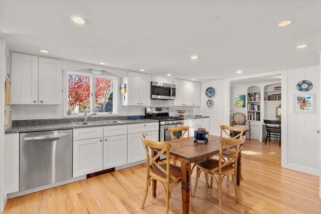 20 Haskell Street Gloucester, MA 01930 - Photo 6 of 27 a kitchen with stainless steel appliances granite countertop a stove top oven a sink a dining table and chairs with wooden floor