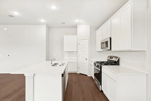 a kitchen with stainless steel appliances a sink stove and cabinets