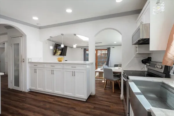 a kitchen with white cabinets and wooden floors