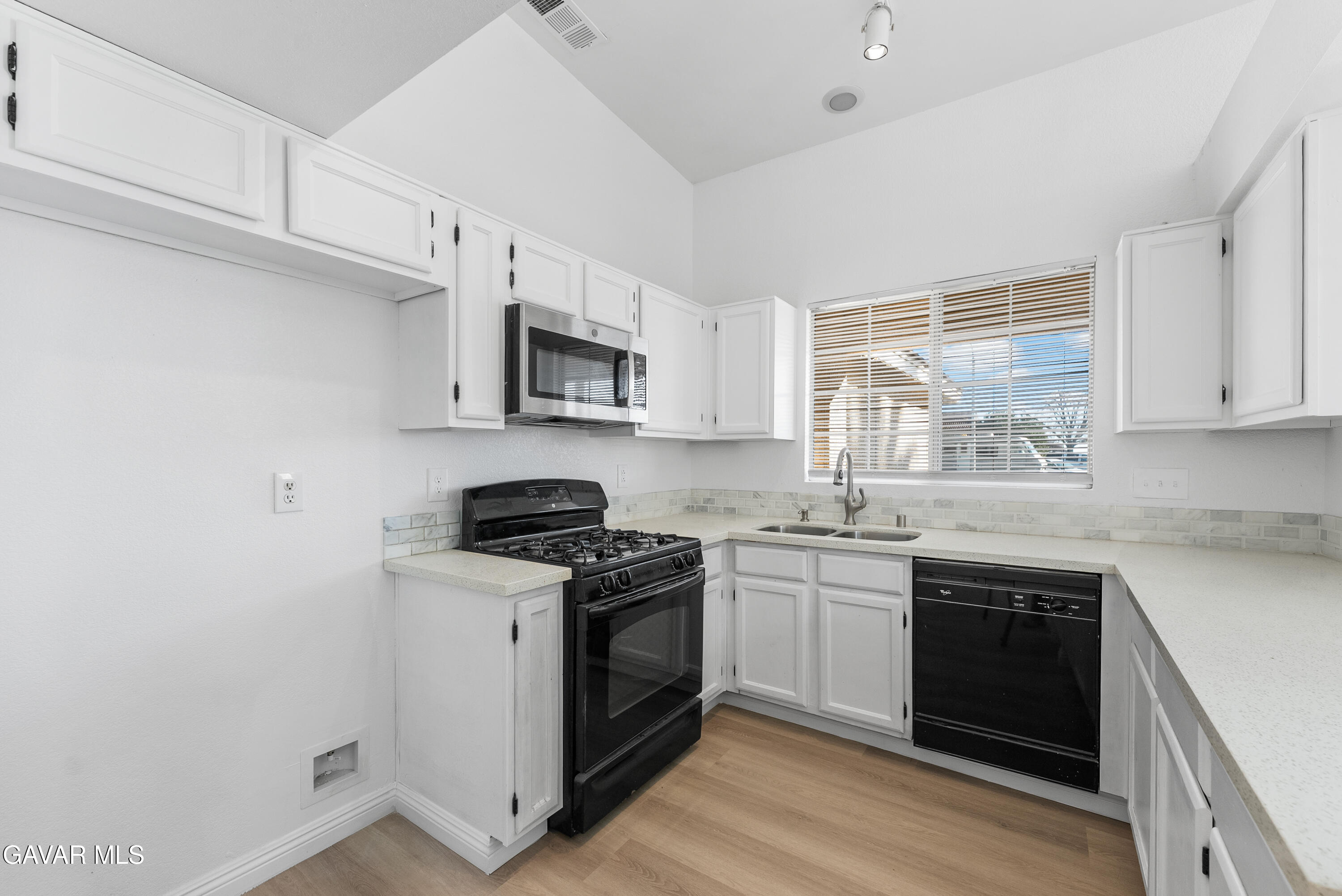 3209 Titcher Lane Rosamond, CA 93560 - Photo 5 of 36 a kitchen with stainless steel appliances granite countertop white cabinets a sink a stove a microwave and wooden floors
