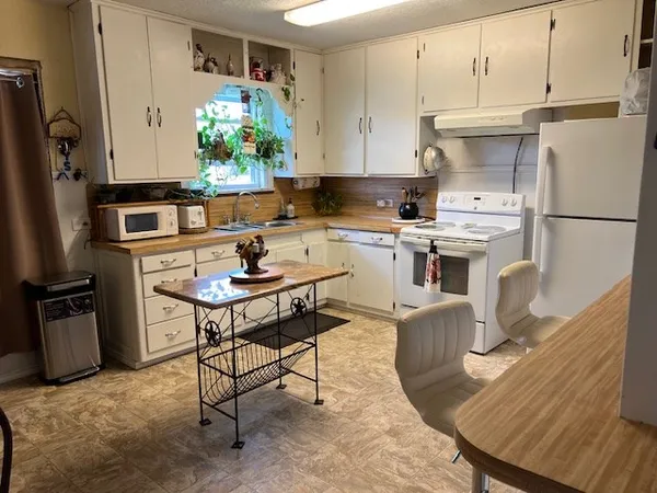 a kitchen with stainless steel appliances granite countertop a refrigerator a stove a sink dishwasher and white cabinets with wooden floor