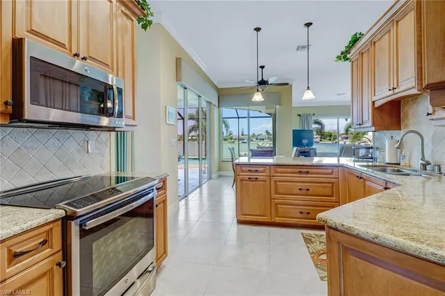 a kitchen with stainless steel appliances granite countertop a sink a stove and a wooden cabinets