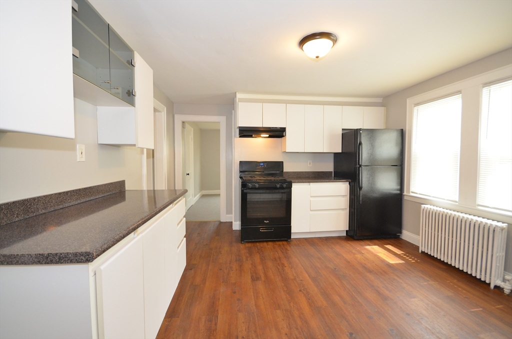 75 Beacon Street, Unit 1 Lawrence, MA 01843 - Photo 3 of 22 a kitchen with granite countertop wooden floors and stainless steel appliances