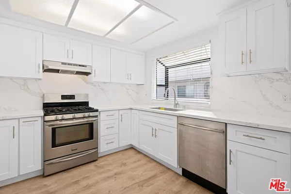a kitchen with cabinets stainless steel appliances and sink
