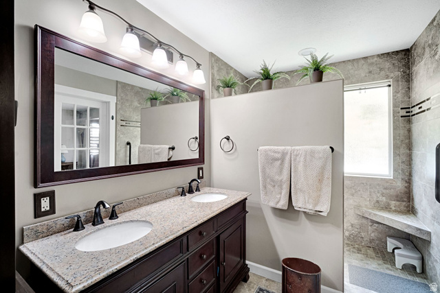 2139 Village Point Way Sandy, UT 84093 - Photo 14 of 35 Updated primary bathroom featuring a dual sink vanity with granite countertop and dark wood-finish cabinetry. Large walk in shower.