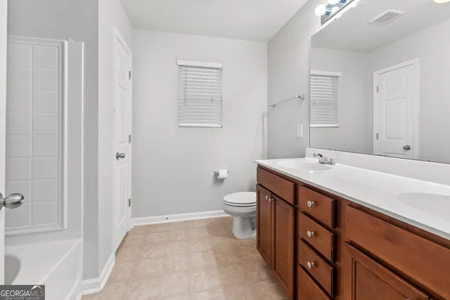 a spacious bathroom with a double vanity sink a toilet and a mirror