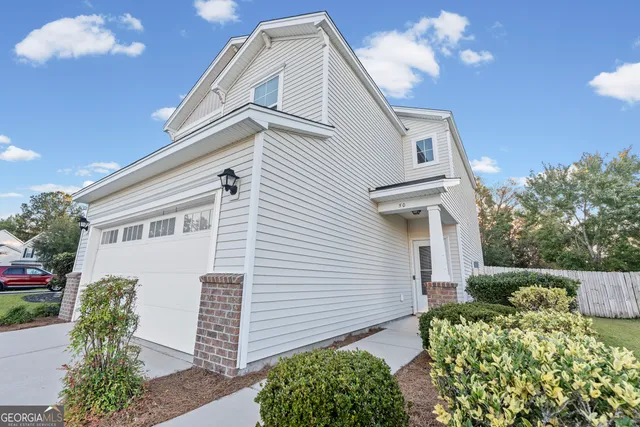 a view of a white house with a large window and potted plants