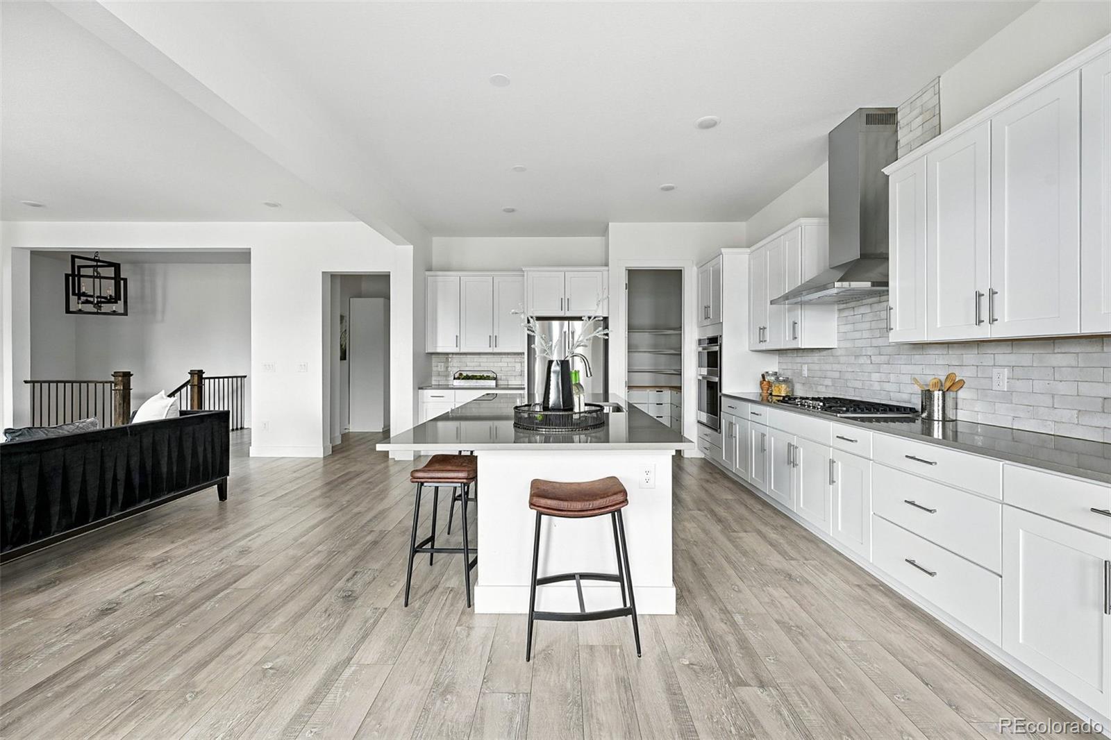 4855 Saddle Iron Road Castle Rock, CO 80104 - Photo 14 of 50 a kitchen with stainless steel appliances granite countertop a refrigerator a stove top oven a sink dishwasher and white cabinets with wooden floor