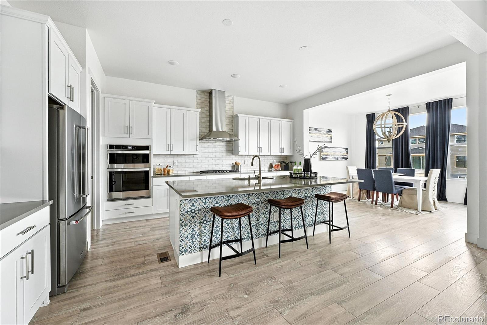 4855 Saddle Iron Road Castle Rock, CO 80104 - Photo 7 of 50 a kitchen with stainless steel appliances kitchen island granite countertop a table chairs microwave and sink
