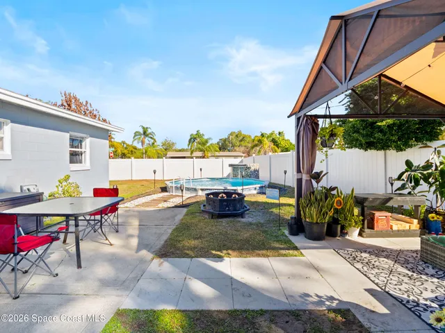 a view of yard from a patio with dining table and chairs