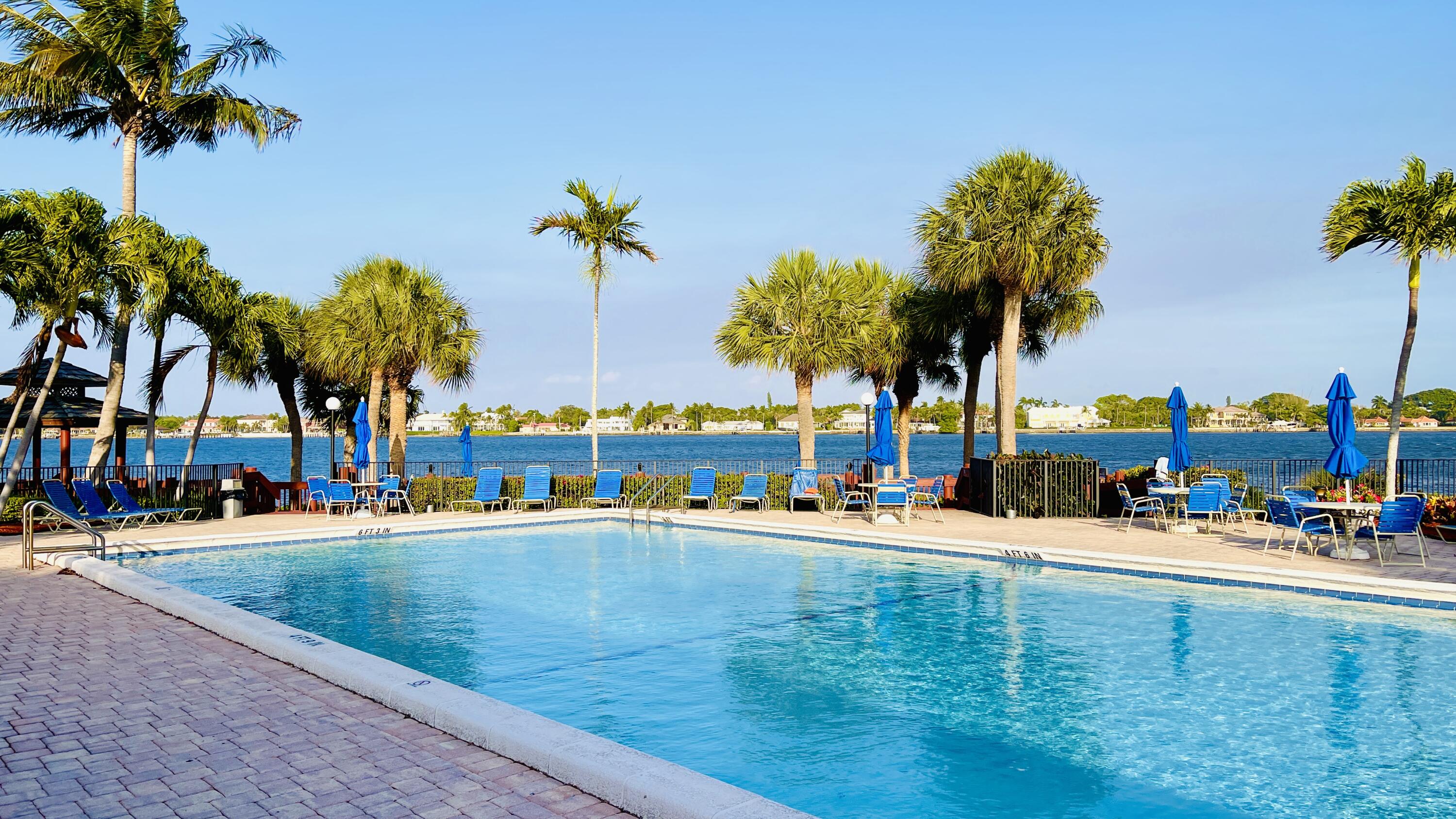 104 Half Moon Circle, Unit B2 Hypoluxo, FL 33462 - Photo 16 of 54 a view of a swimming pool with a lawn chairs under palm trees