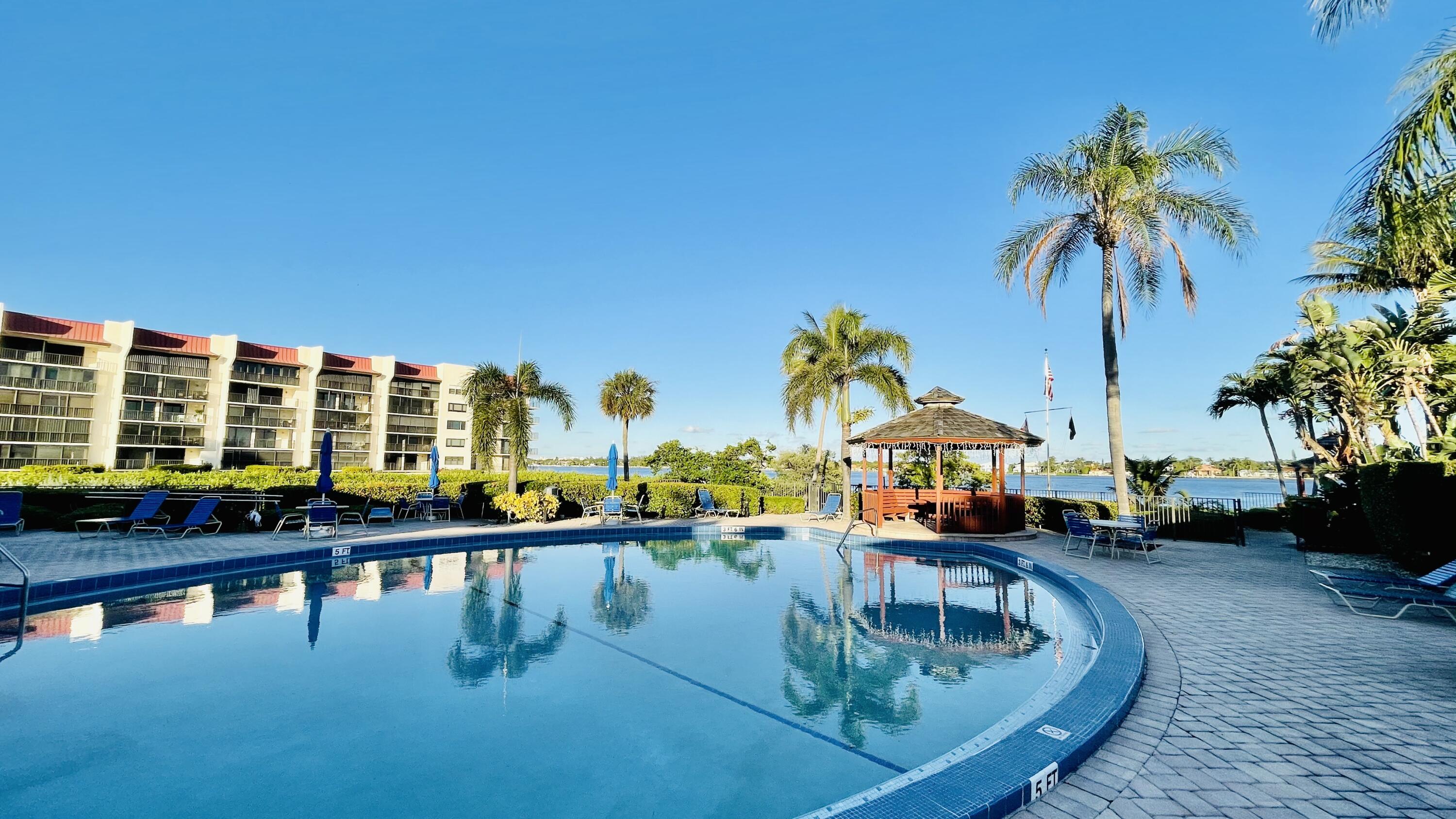 104 Half Moon Circle, Unit B2 Hypoluxo, FL 33462 - Photo 21 of 54 a swimming pool with outdoor seating and a garden