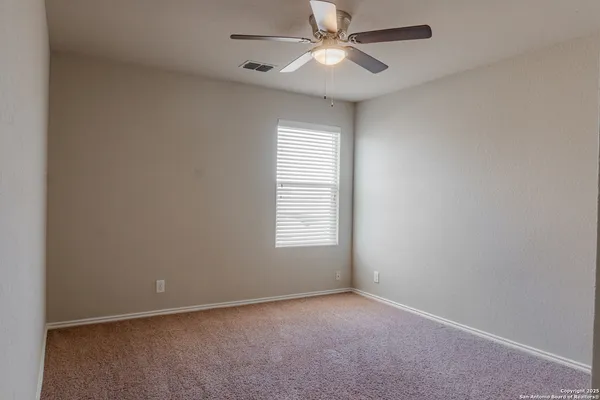 an empty room with a window and a fan