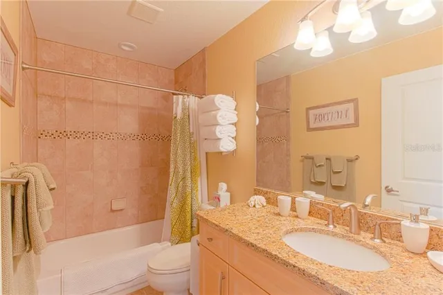 a bathroom with a granite countertop sink a toilet and shower