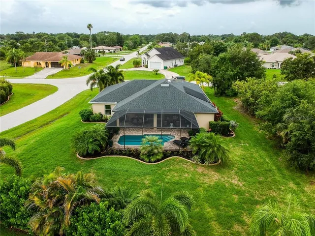 an aerial view of residential houses with outdoor space and trees