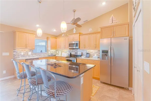 a kitchen with stainless steel appliances granite countertop a sink a stove a refrigerator and island