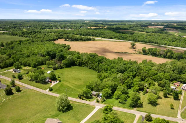 an aerial view of a residential houses with outdoor space and trees all around