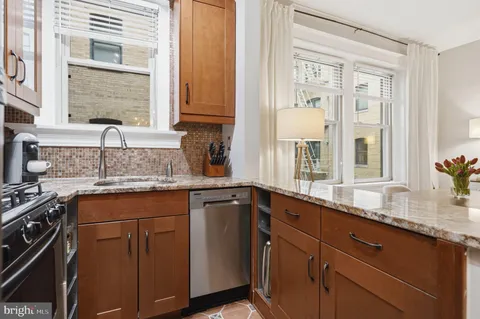a kitchen with granite countertop cabinets stainless steel appliances a sink and a window
