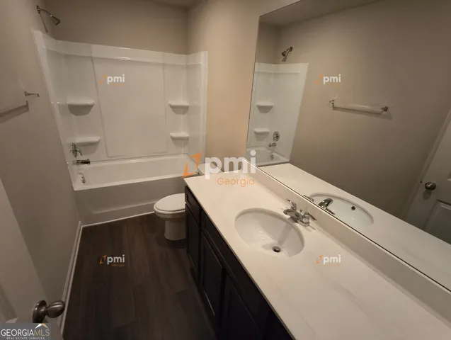 a bathroom with a granite countertop sink a toilet a mirror and shower