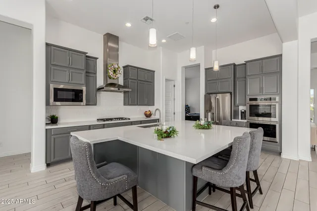 a white kitchen with stainless steel appliances a dining table chairs refrigerator and microwave