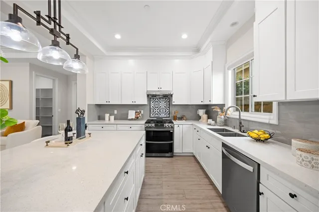 a kitchen with stainless steel appliances granite countertop a sink a stove and white cabinets
