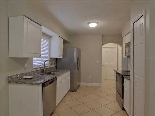 a kitchen that has a sink a refrigerator and cabinets