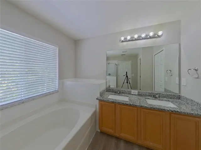 a bathroom with a granite countertop sink a large mirror and a bathtub