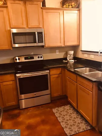 a kitchen with granite countertop a stove microwave and sink