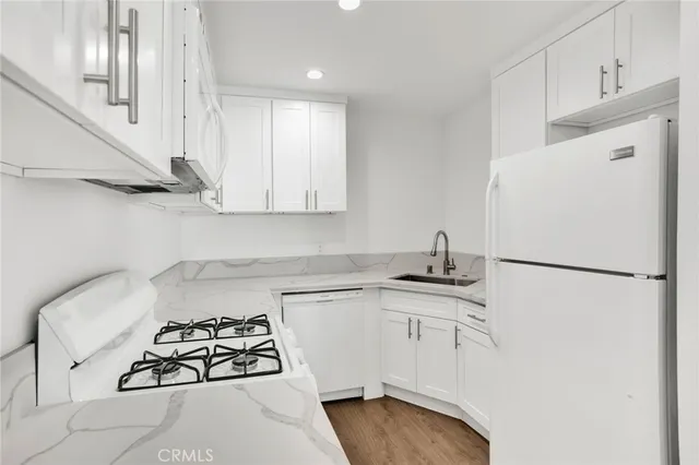 a kitchen with stainless steel appliances a refrigerator a sink and white cabinets