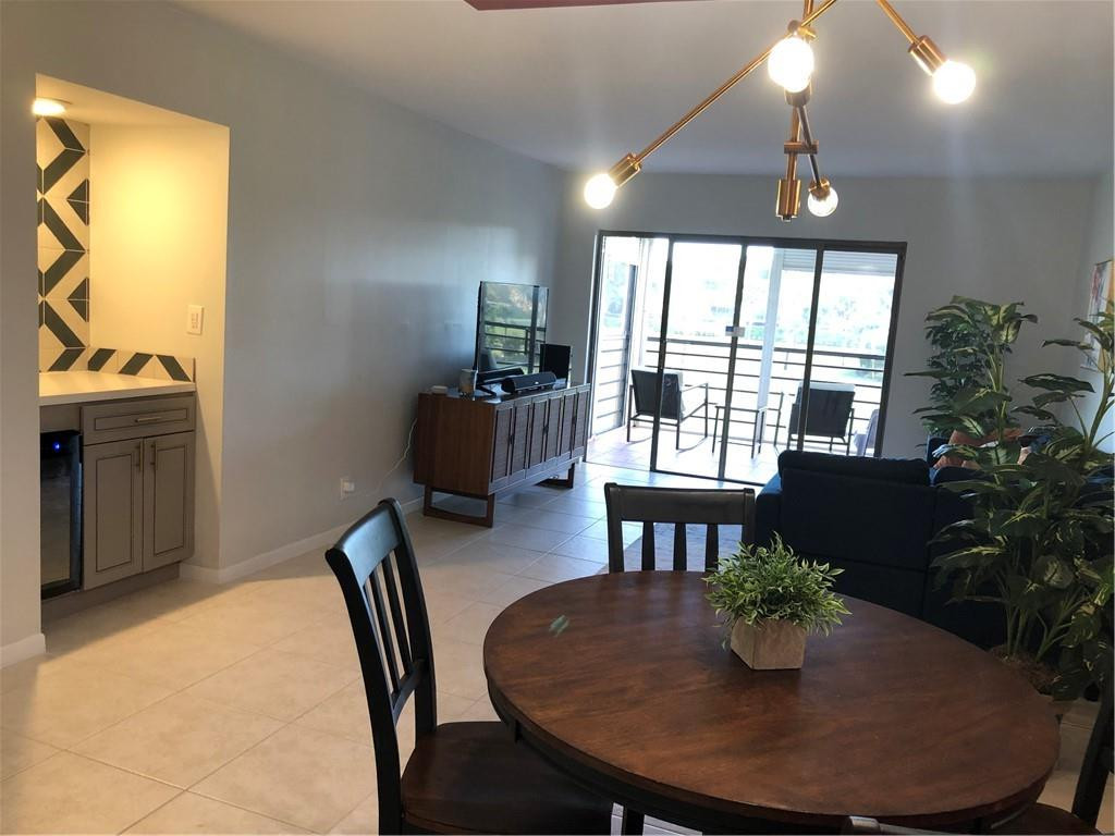 9370 Southwest 8th Street, Unit 323 Boca Raton, FL 33428 - Photo 13 of 17 a dining room with furniture a chandelier and window