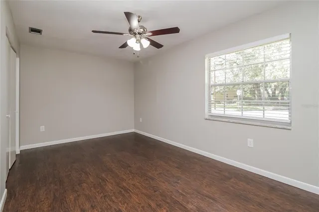 a view of an empty room with wooden floor and a window