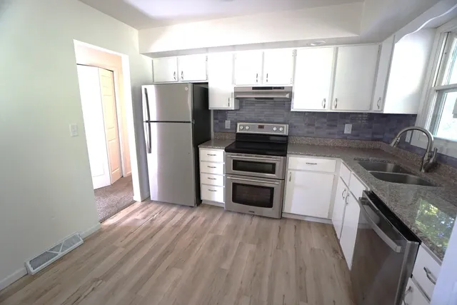 a kitchen with a refrigerator sink and wooden floor