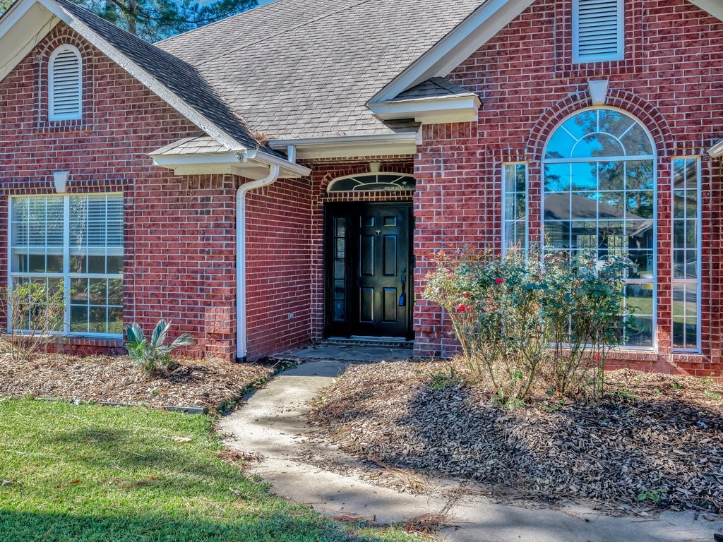 206 Cascade Court Lufkin, TX 75901 - Photo 2 of 27 a view of a brick house with plants and large tree