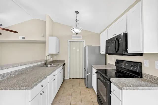 a kitchen with granite countertop a sink a stove top oven and refrigerator