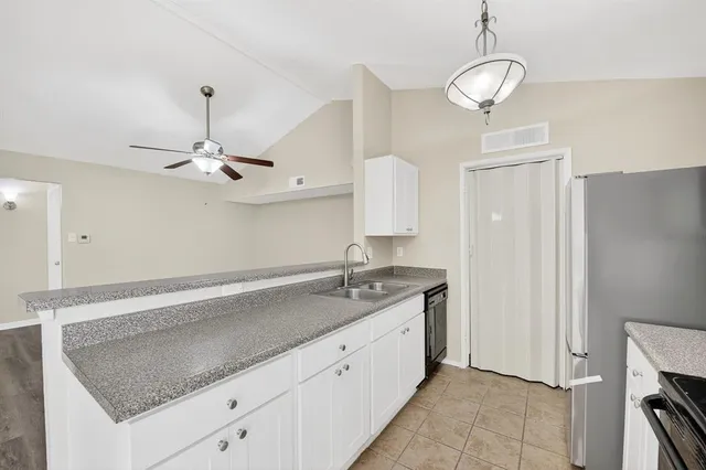 a kitchen with a sink dishwasher and white cabinets with wooden floor